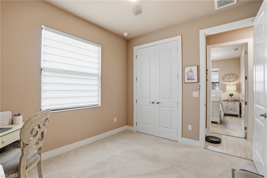 Bedroom featuring light colored carpet, ceiling fan, and healthy amount of natural light