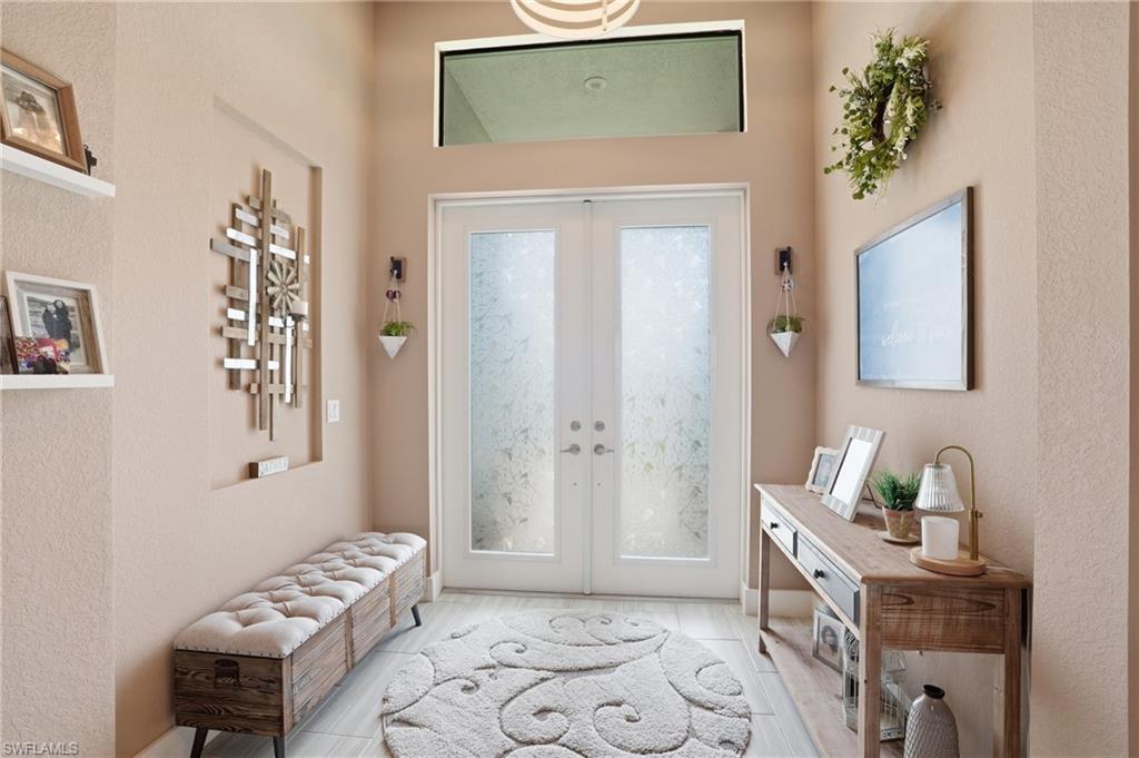 Foyer entrance featuring frosted glass impact doors and a transom