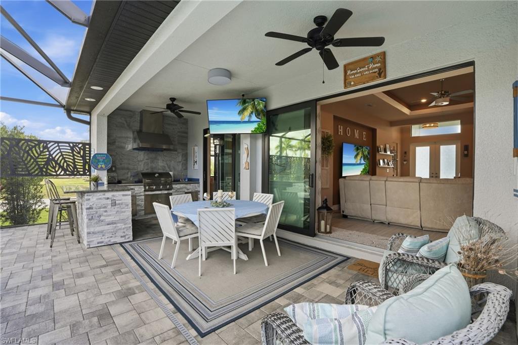 View of patio / terrace with exterior kitchen, an outdoor bar and dining area, a ceiling fan, and screen enclosure, pocket sliders
