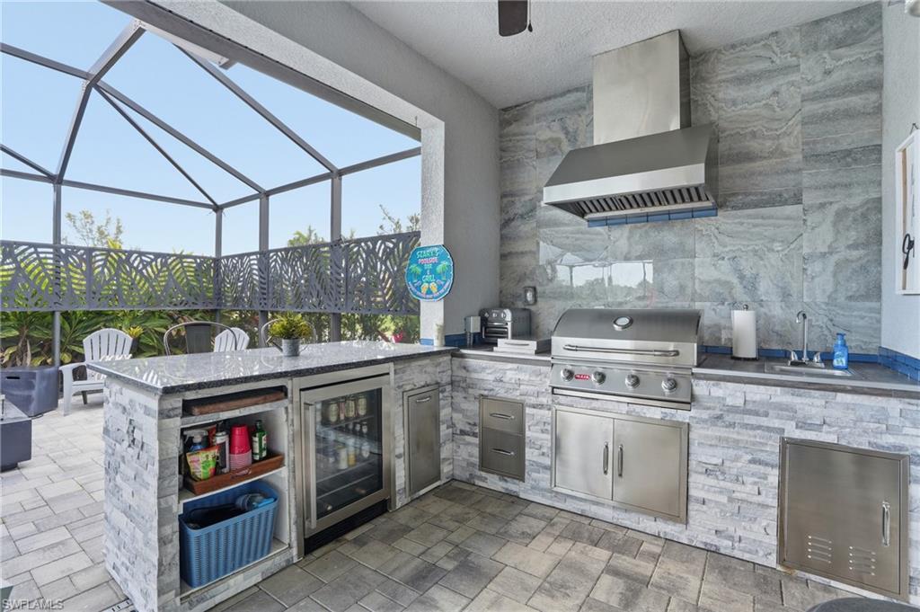 View of patio featuring screen enclosure, outdoor kitchen