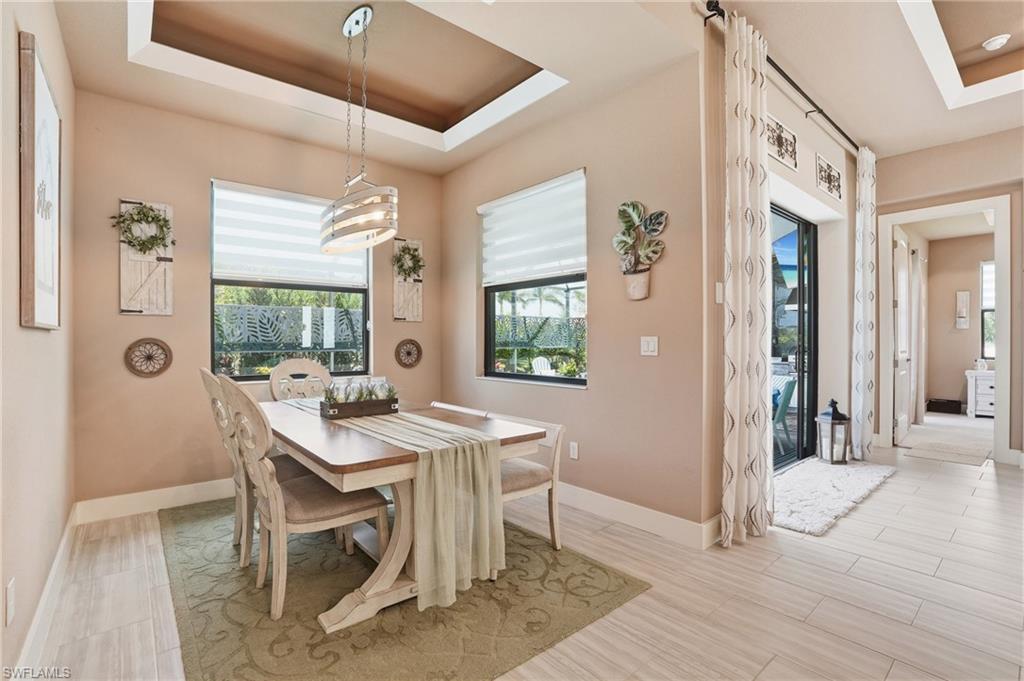 Dining area with a tray ceiling and light wood finished floors