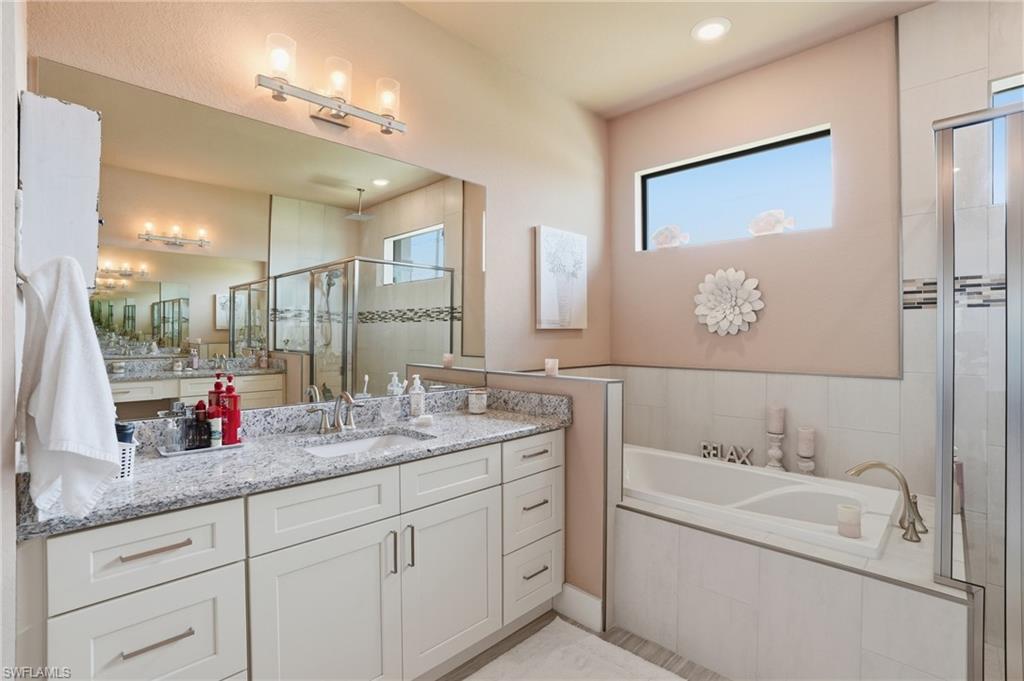 Full bath with a shower stall, vanity, healthy amount of natural light, a bath, and recessed lighting