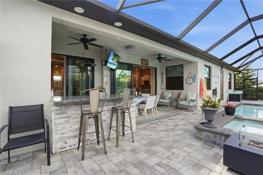 View of patio, ceiling fans, and a pool with connected hot tub