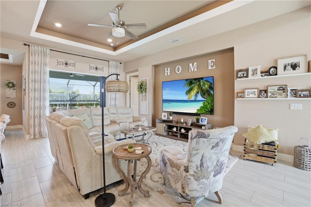 Living room with a ceiling fan, a tray ceiling, and recessed lighting