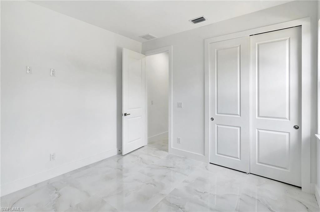 Unfurnished bedroom featuring a closet and light marble finish floors
