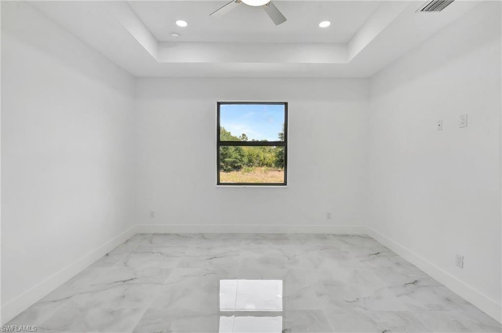 Unfurnished room featuring a raised ceiling, ceiling fan, and recessed lighting