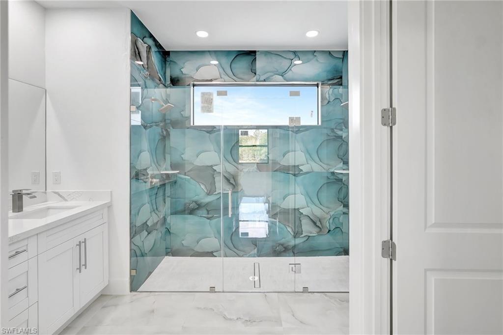 Bathroom with vanity, a marble finish shower, and recessed lighting
