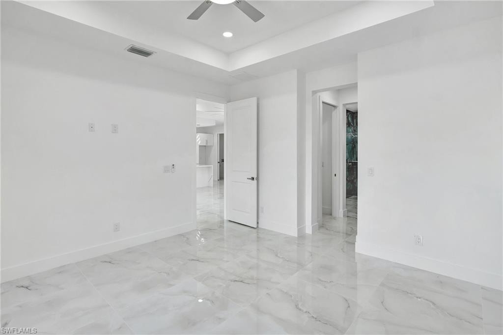 Unfurnished bedroom featuring ceiling fan, a tray ceiling, and recessed lighting