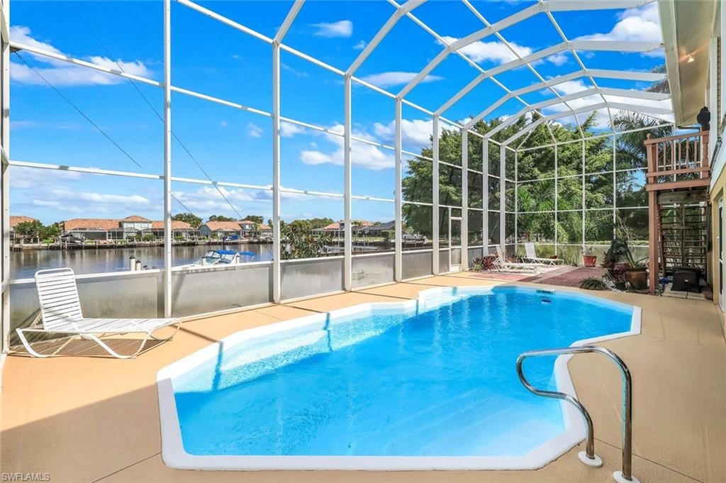 Outdoor pool featuring a sunroom, a lanai, a patio, and a water view