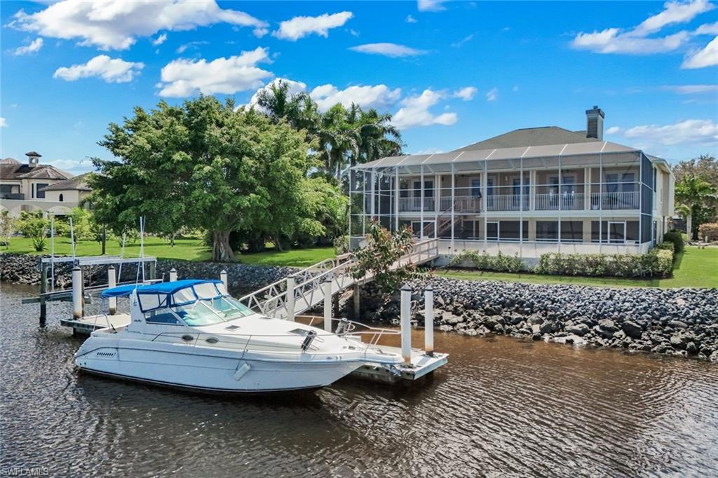 Dock area with a water view, a yard, and a sunroom