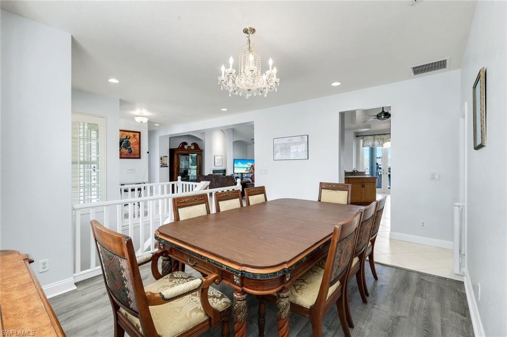 Dining space with suspended lighting, light wood-type flooring, ceiling fan, and arched walkways