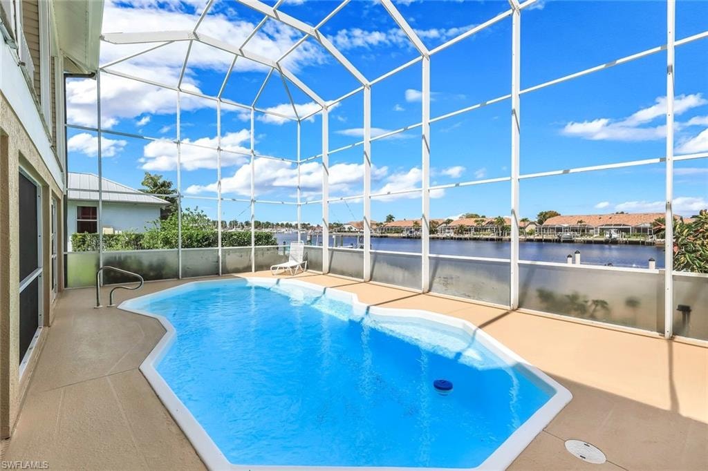 Swimming pool with glass enclosure, a sunroom, a patio area, and a residential view