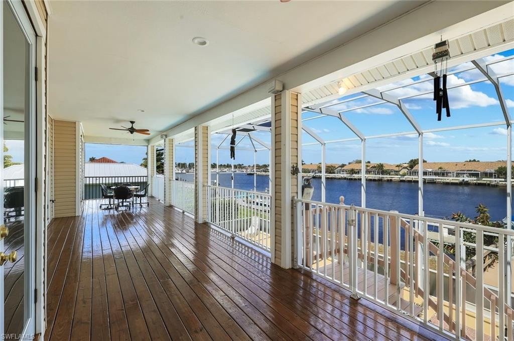 Deck featuring a ceiling fan, a water view, and glass enclosure