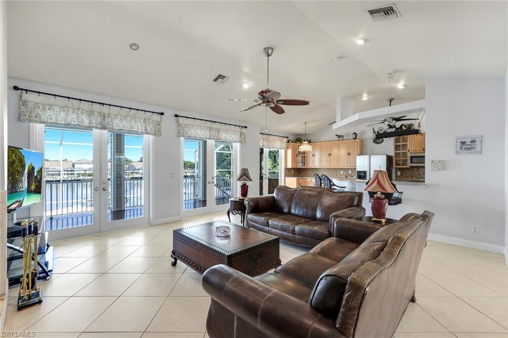 Living room featuring a ceiling fan, a water view, light tile patterned floors, lofted ceiling, and french doors