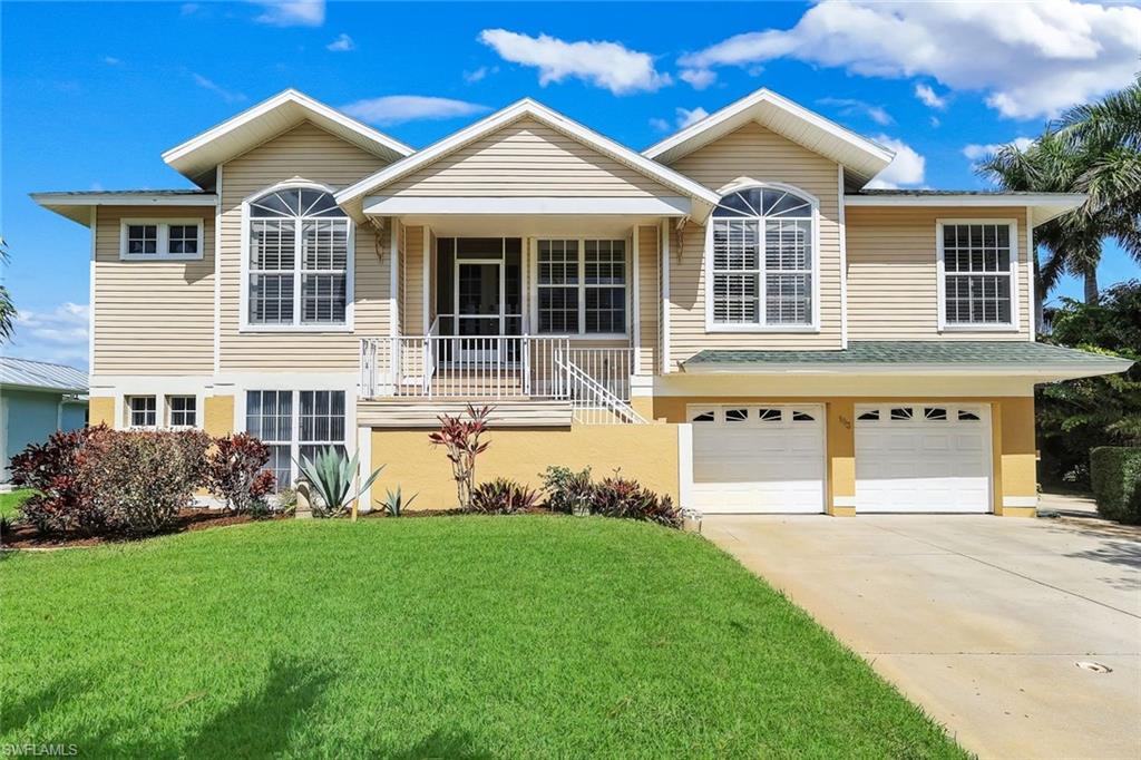 View of front facade featuring driveway, a balcony, an attached garage, and a front lawn