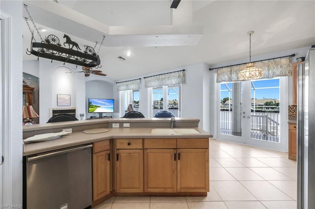 Kitchen featuring stainless steel appliances, wood finish cabinetry, open floor plan, ceiling fan, and a fireplace