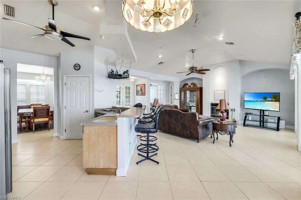 Kitchen featuring ceiling fan, hanging lights, a breakfast bar, open floor plan, and light countertops
