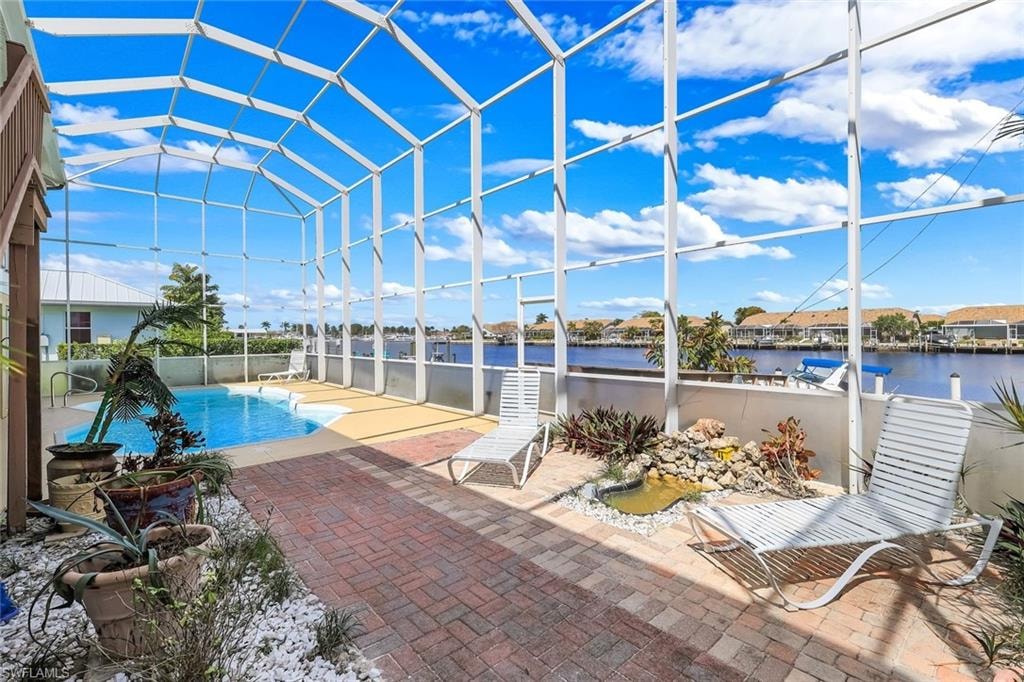 View of pool with a lanai, a sunroom, patio surround, and a water view