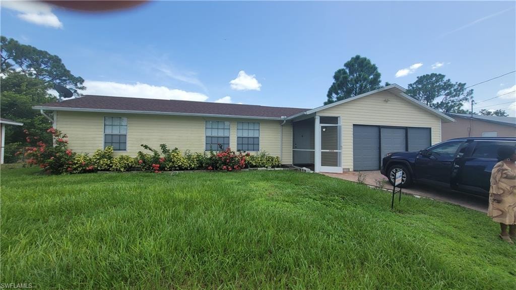 Single story home with a garage and a front lawn
