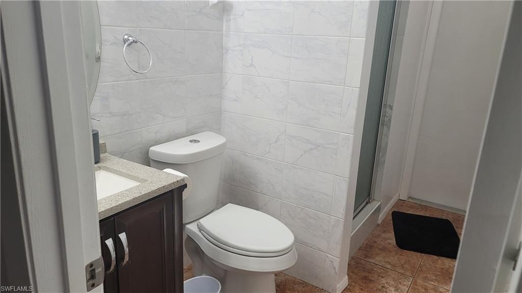 Bathroom featuring tile walls, tile patterned floors, toilet, and vanity