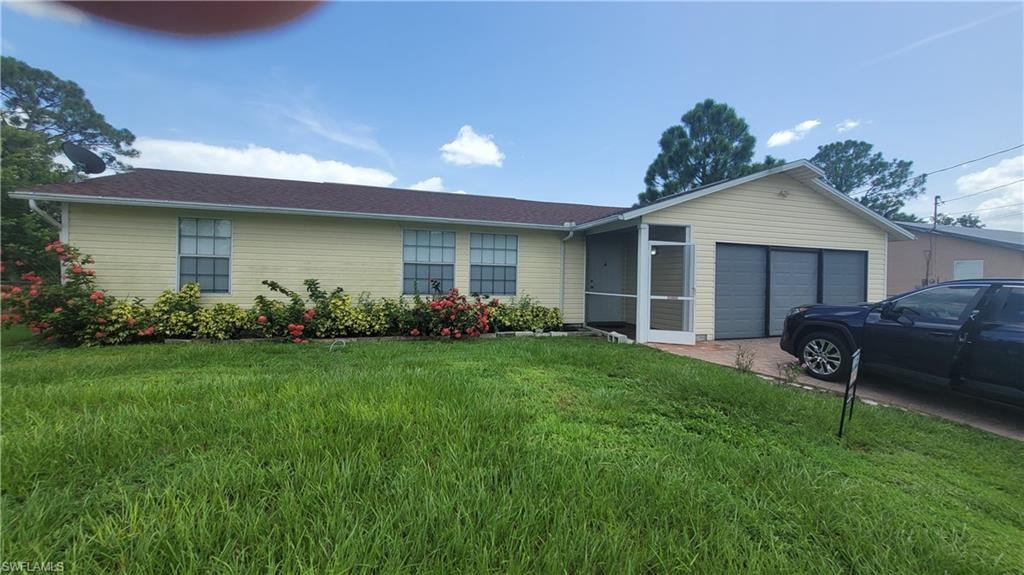Single story home with a garage and a front lawn