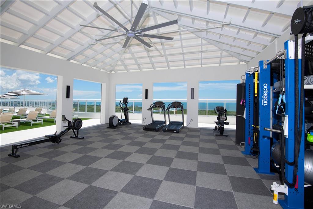 Exercise room featuring a high ceiling, a water view, and a ceiling fan