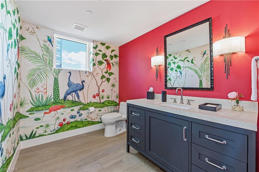 Bathroom with vanity, light wood-style floors, and an accent wall