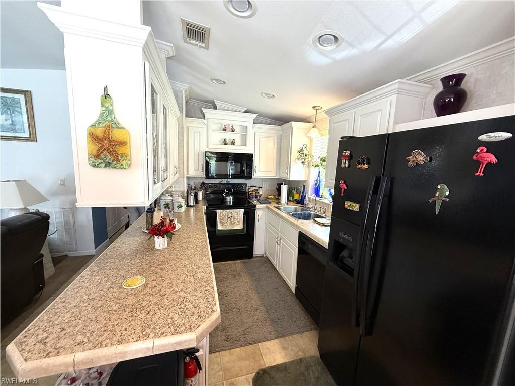 Kitchen featuring black appliances, white cabinets, and lofted ceiling