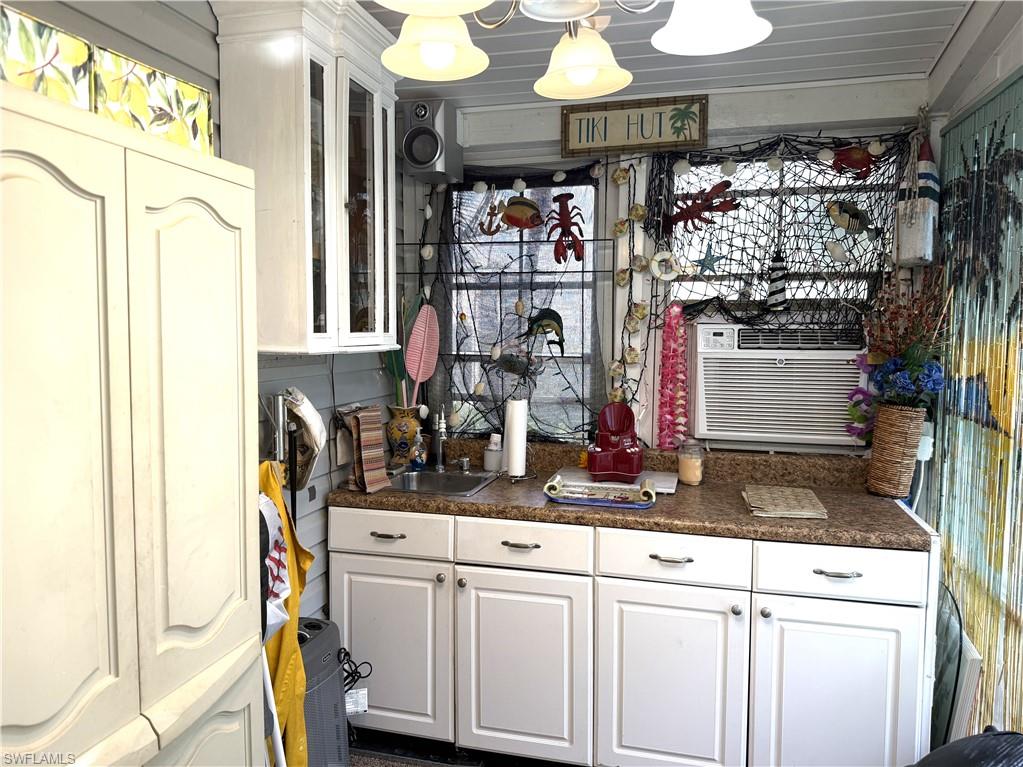Bar with white cabinets, glass insert cabinets, and dark countertops