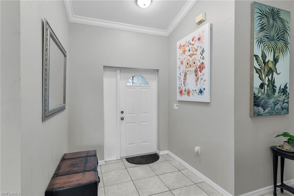 Foyer with ornamental molding and light tile patterned flooring