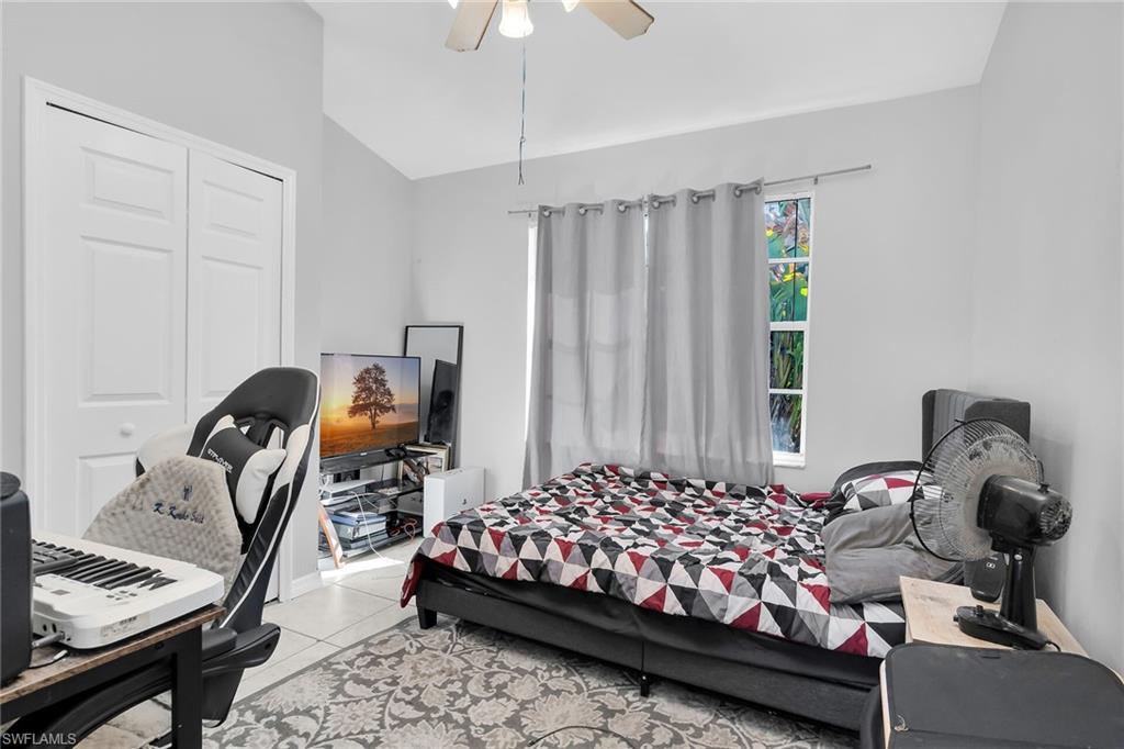 Bedroom with lofted ceiling, tile patterned floors, and ceiling fan