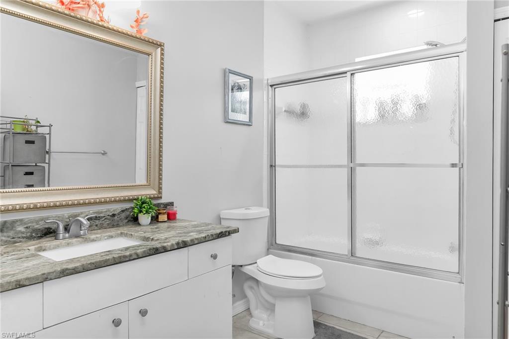 Full bathroom featuring vanity, enclosed tub / shower combo, and light tile patterned floors