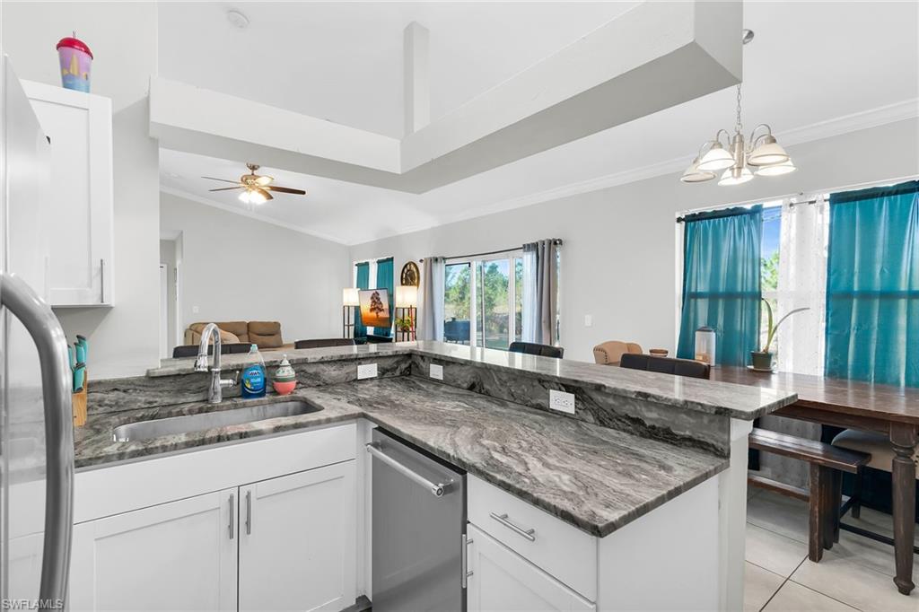 Kitchen with open floor plan, white cabinetry, dark stone countertops, a chandelier, and stainless steel appliances