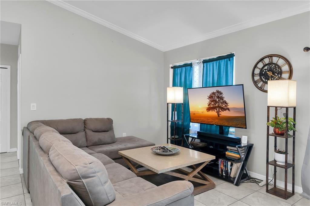 Living area featuring crown molding and light tile patterned flooring