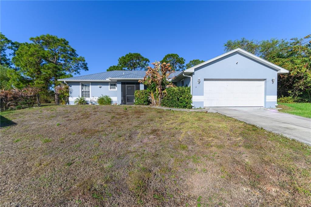 Ranch-style home with stucco siding, an attached garage, driveway, and a metal roof