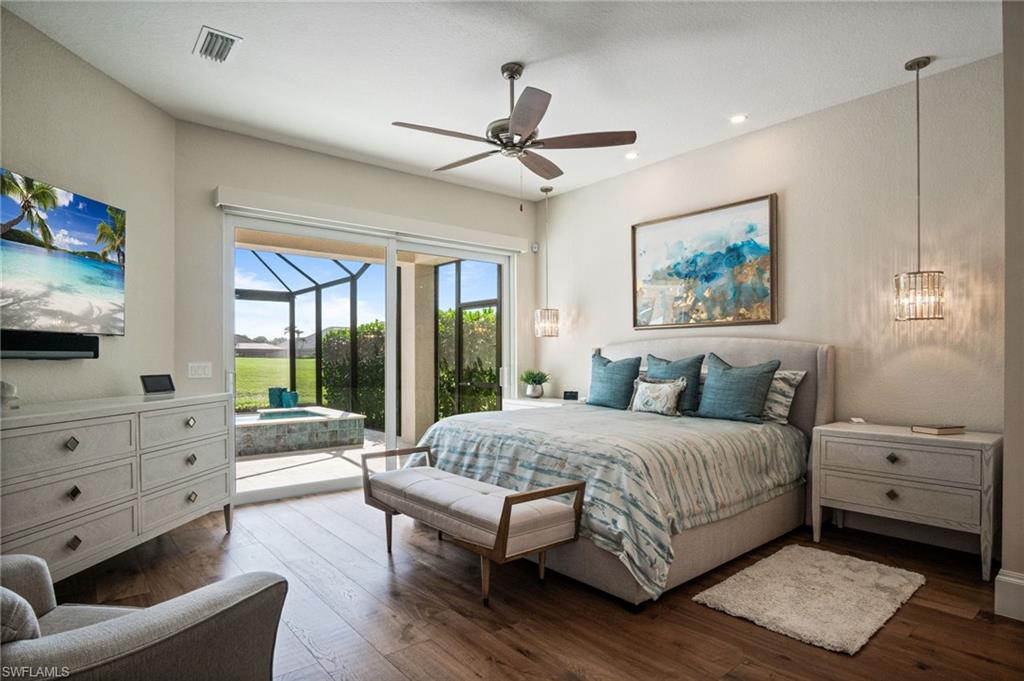 Spacious primary suite offers private access to the lanai along with a spa-like en-suite bath featuring TAJ MAHAL quartzite countertops, dual vanities, and a large glass-enclosed shower.