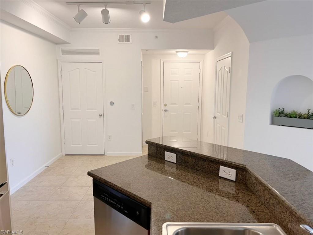 Kitchen featuring track lighting, dishwasher, crown molding, and light tile patterned floors