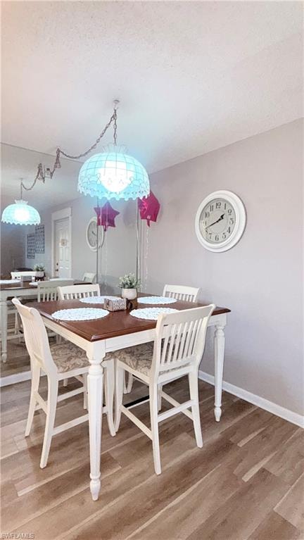Dining space with light wood-style flooring and a textured ceiling