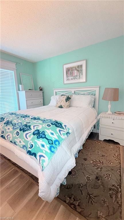 Bedroom with wood finished floors and a textured ceiling