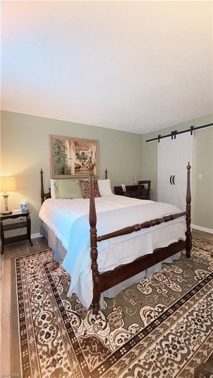 Bedroom with dark wood-style floors and a barn door
