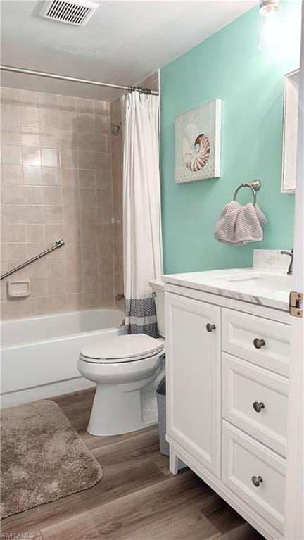 Bathroom featuring vanity, shower / bath combo, and wood finished floors