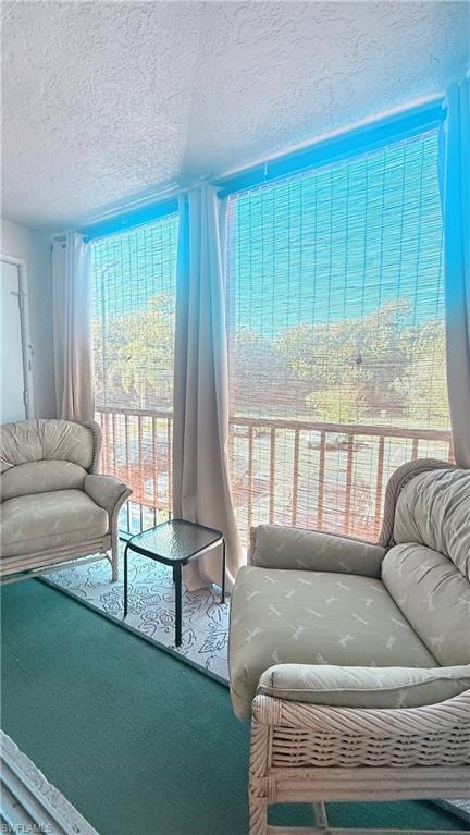 Carpeted living area featuring a textured ceiling
