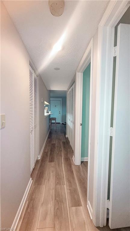 Hall with baseboards and light wood-style floors
