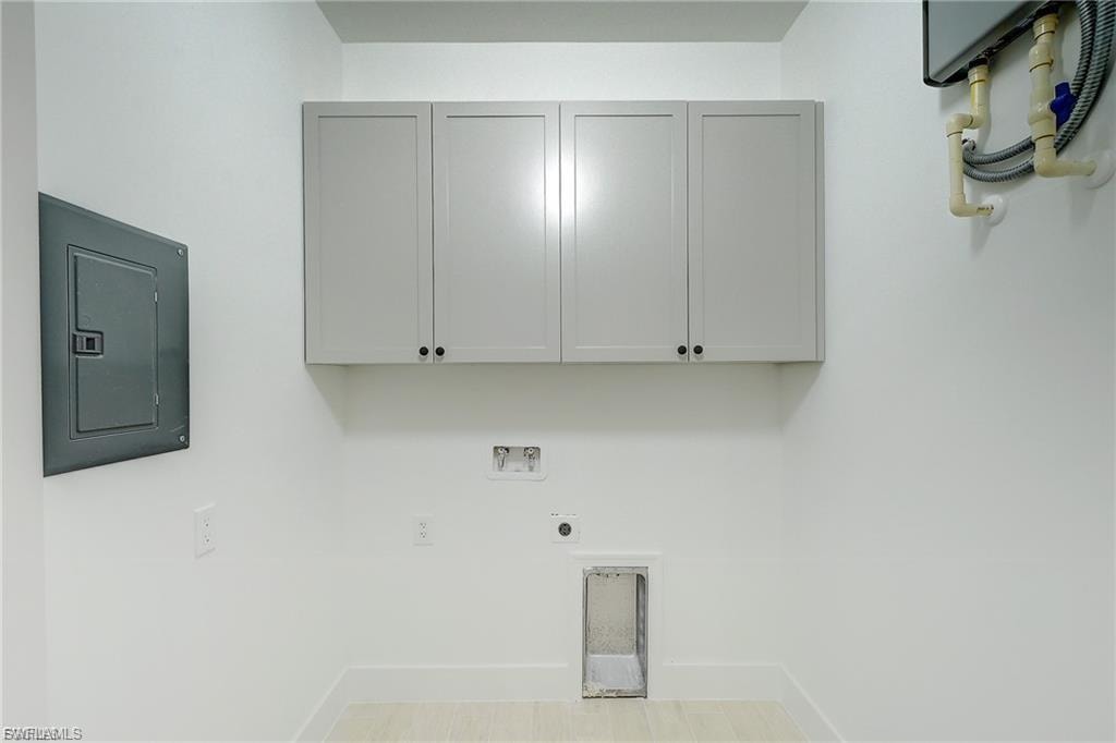Laundry room featuring electric panel, cabinet space, hookup for a washing machine, and electric dryer hookup