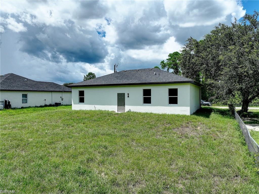 Rear view of house featuring stucco siding and a yard