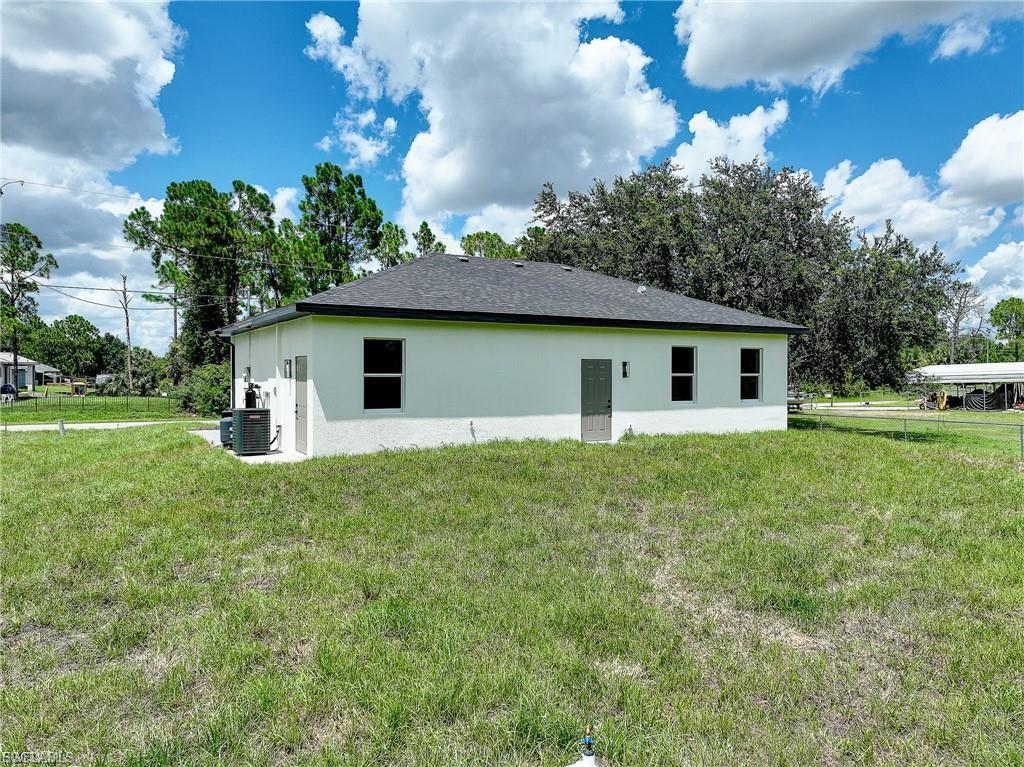 View of side of home featuring stucco siding and a lawn