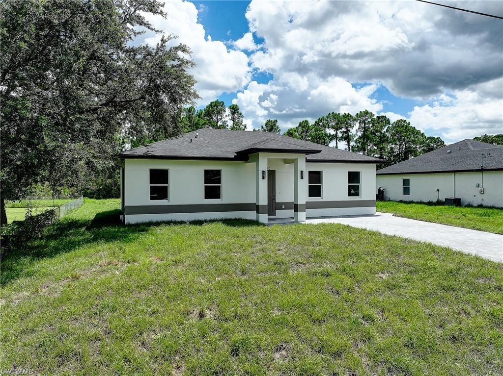 View of front of property featuring a front yard, stucco siding, and driveway