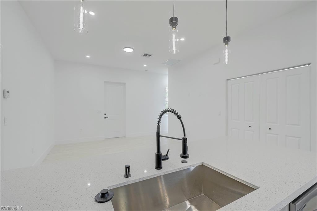 Kitchen view of light stone countertops and pendant lighting