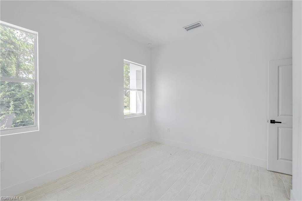 Empty room featuring baseboards and light wood-type flooring
