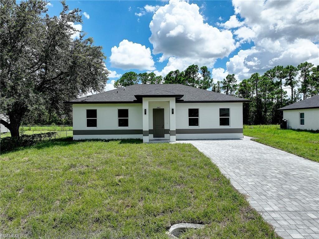 View of front of property with a front lawn, stucco siding, and decorative driveway